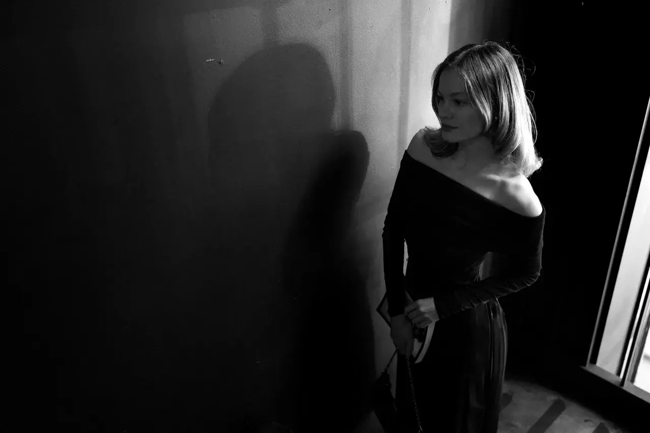 Eine Frau in einem eleganten, schulterfreien Kleid wartet im Schatten. Perfekt für einen Anlass mit "black tie optional"-Dresscode.