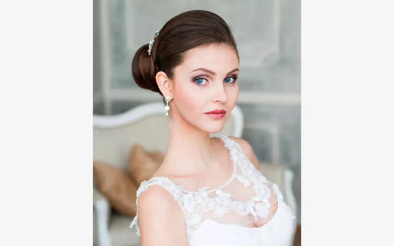 Panna młoda z eleganckim upięciem i biżuterią, w białej sukni.