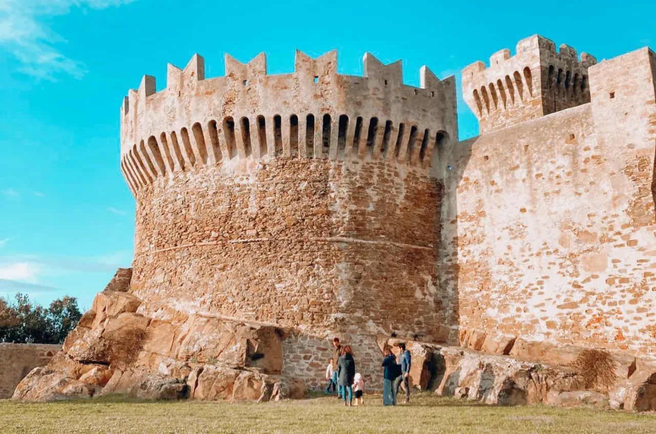 Antica fortezza in pietra, uno dei borghi vicino Livorno, con una famiglia che passeggia sull'erba.