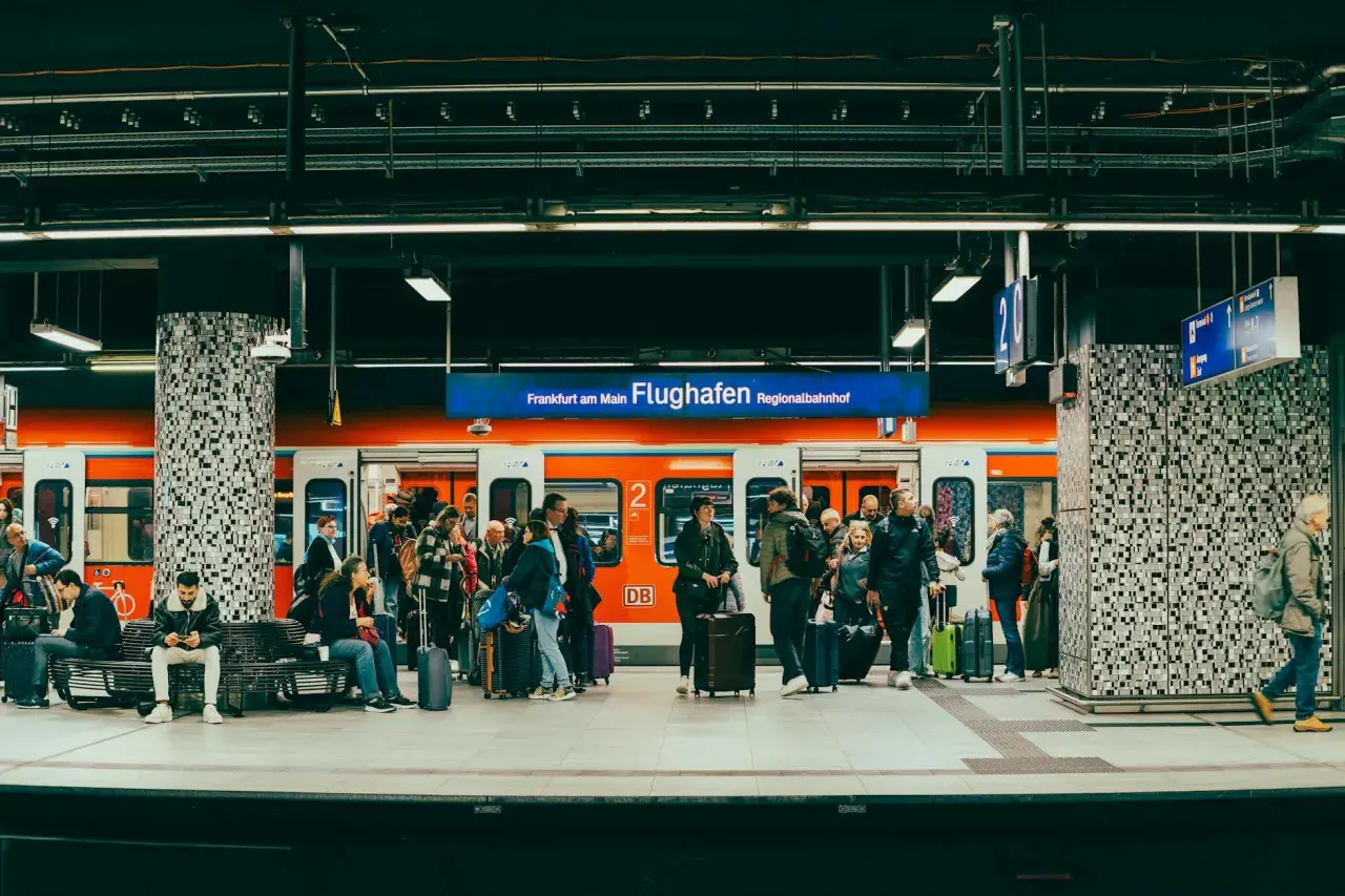 Ludzie z bagażami czekają na pociąg na stacji Frankfurt am Main Flughafen Regionalbahnhof.