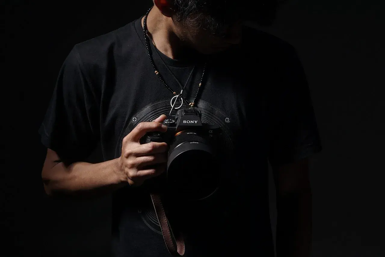 Mężczyzna w czarnej koszulce trzyma aparat Sony. Może to być jego zgłoszenie do konkursu fotograficznego.