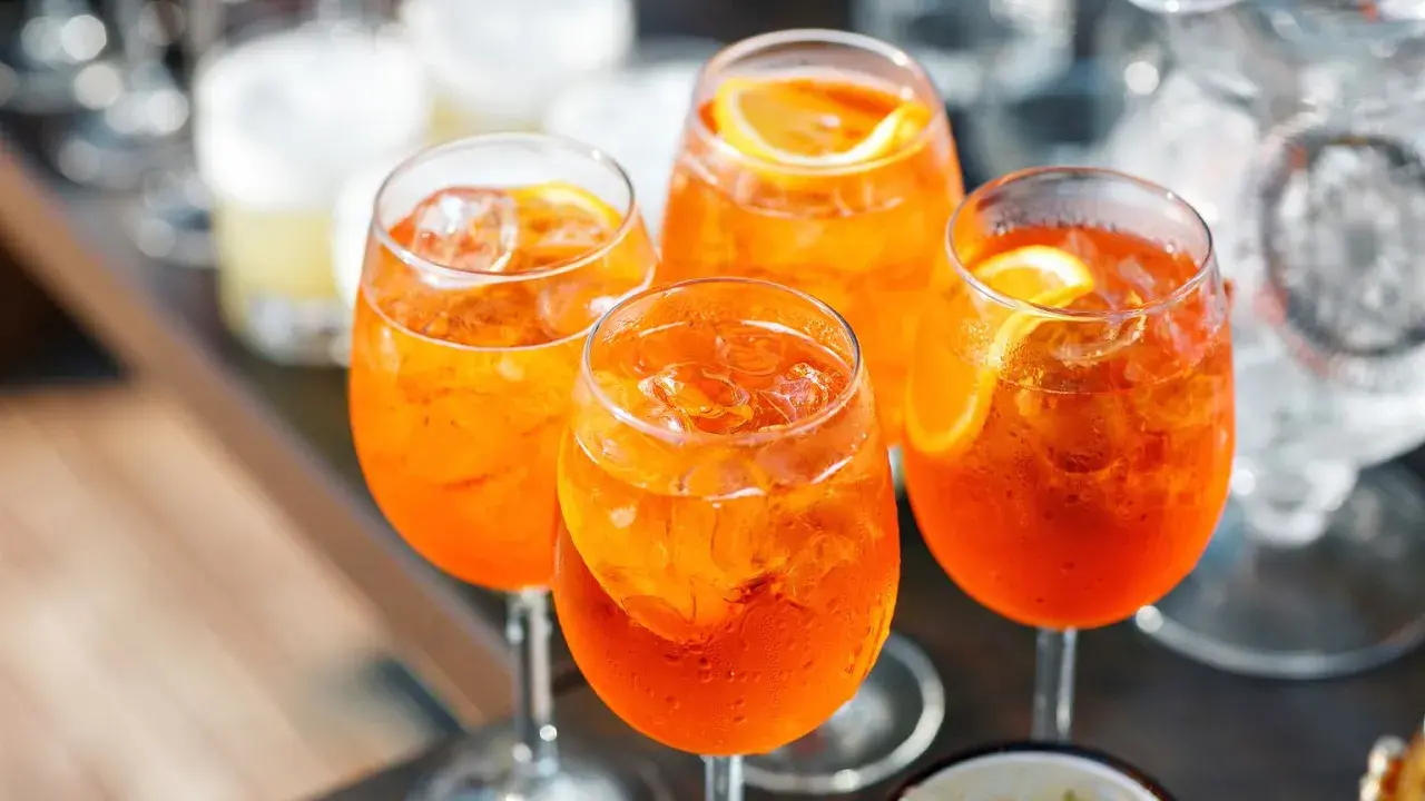 Cztery orzeźwiające drinki Aperol Spritz z lodem i plasterkami pomarańczy. Idealny aperol przepis na letnie popołudnie.