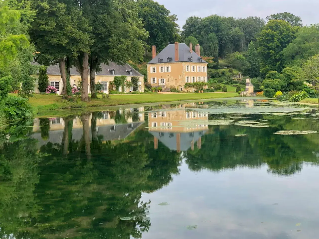 Le jardin du Plessis Sasnières, avec son étang paisible reflétant le château et ses arbres majestueux, offre une vue d'une beauté intemporelle.