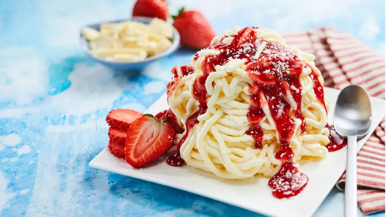 Ein köstliches Spaghetti-Eis-Dessert mit Erdbeersauce und frischen Erdbeeren.