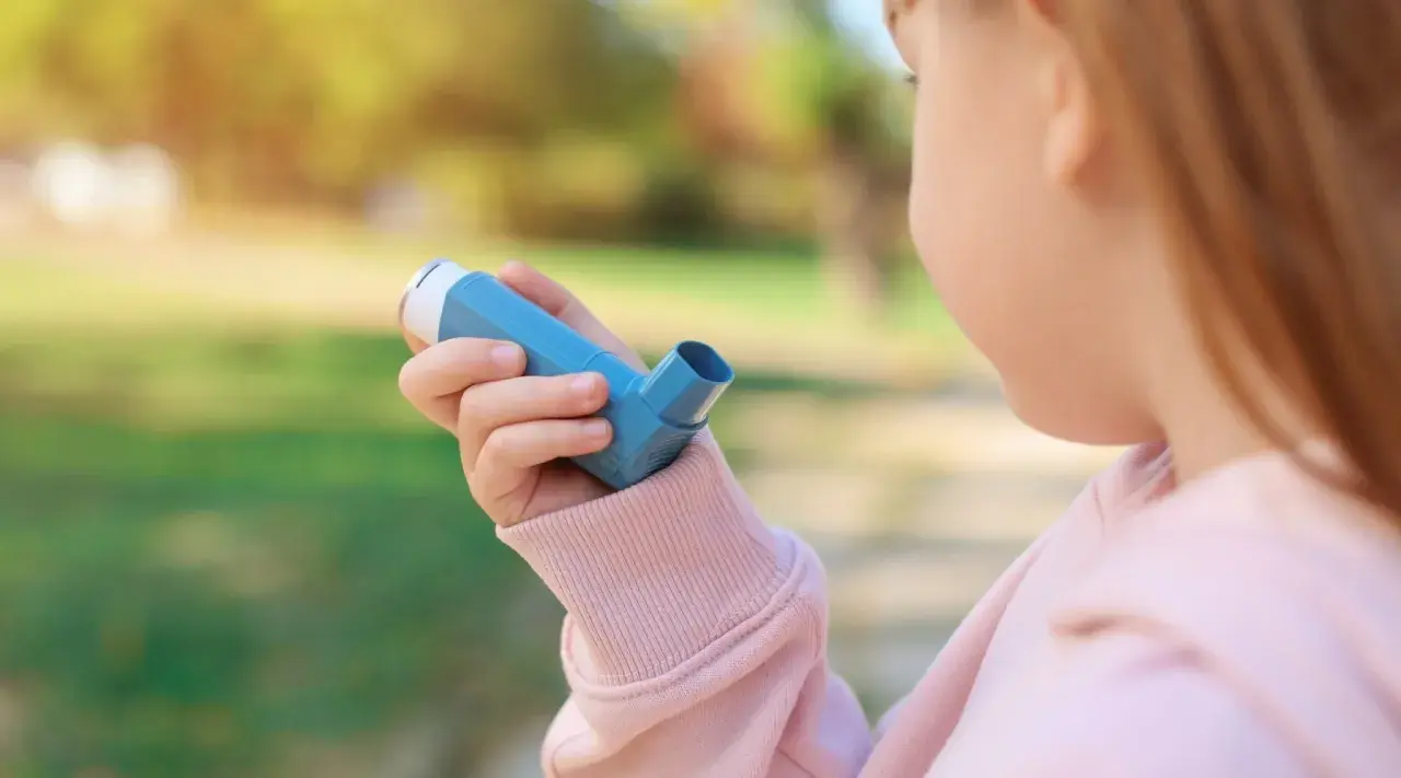 Bambina con inalatore blu, per gestire la tosse asmatica e i suoi sintomi.