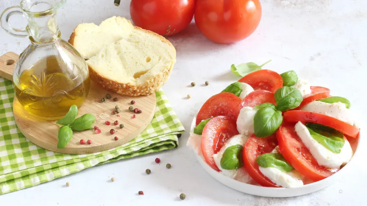 Un'incredibile insalata caprese, con pomodori freschi, mozzarella e basilico, pronta per essere condita con olio d'oliva.