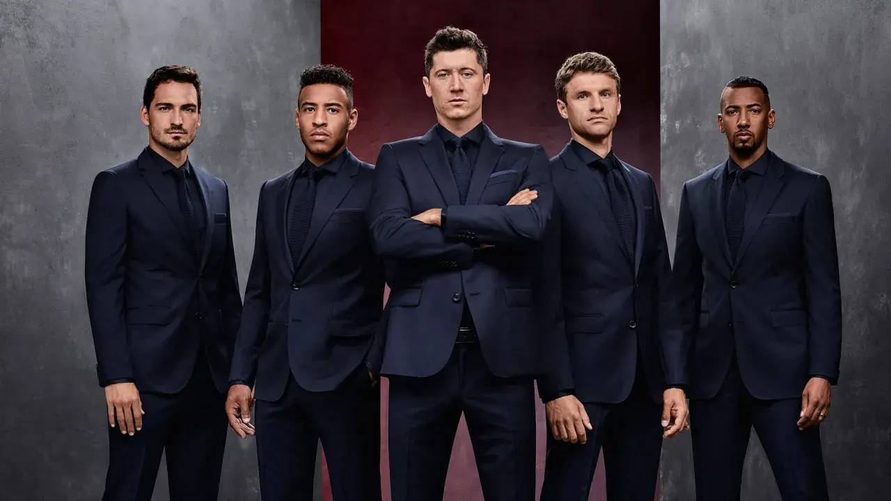 Pięciu mężczyzn w granatowych garniturach, prezentujących elegancję marki Hugo Boss.