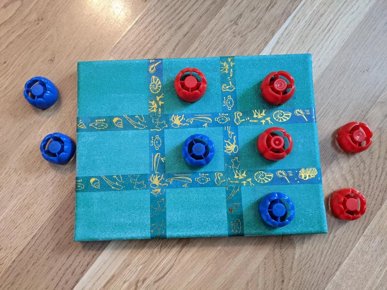Selbstgemachtes Spielbrett mit blauen und roten Spielfiguren. Ein tolles Bastelprojekt für Kinder!