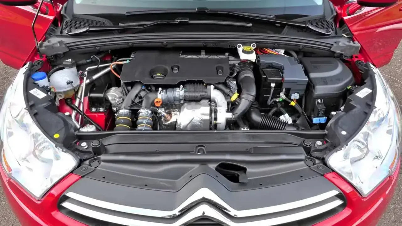 Silnik w czerwonym Citroen C4 2008. Widok komory silnika z turbosprężarką i przewodami.