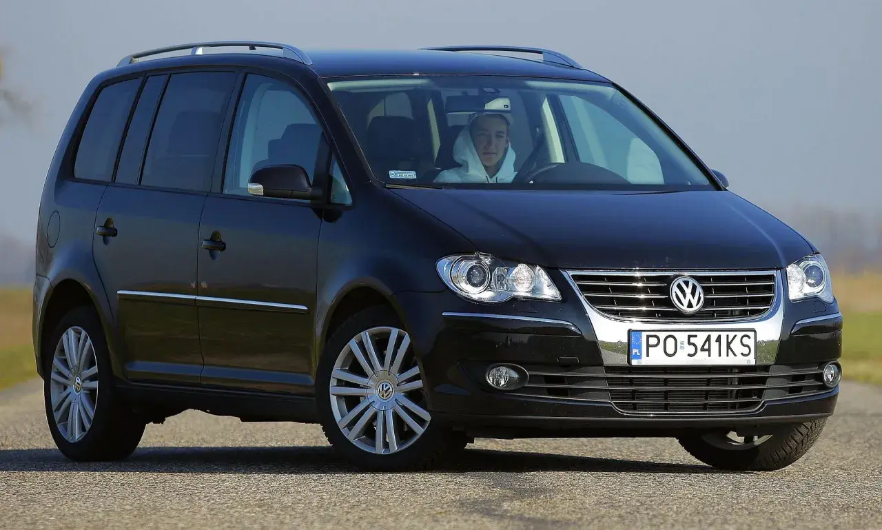 Czarny Volkswagen Touran 2004 z kierowcą w kapturze, widok z przodu.