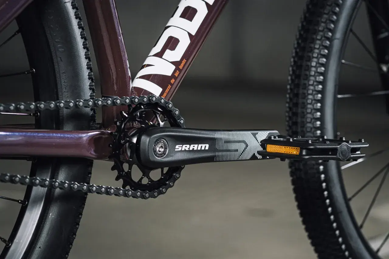 Zbliżenie na rowerowy mechanizm korbowy SRAM i łańcuch. Tabela przełożeń rowerowych jest kluczowa dla optymalnego pedałowania.