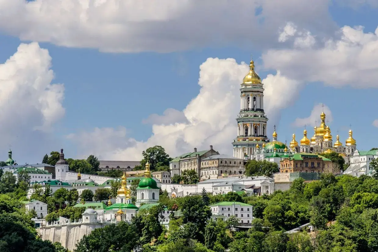 Kijów, z czego słynie Ukraina: złote kopuły cerkwi i majestatyczna dzwonnica Ławry Peczerskiej na tle błękitnego nieba.