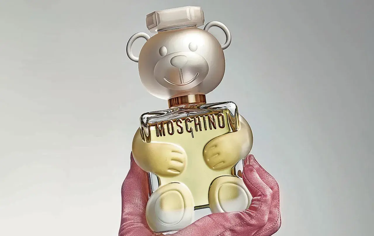 Różowe rękawiczki trzymają uroczy flakon perfum Moschino Toy 2 w kształcie misia.