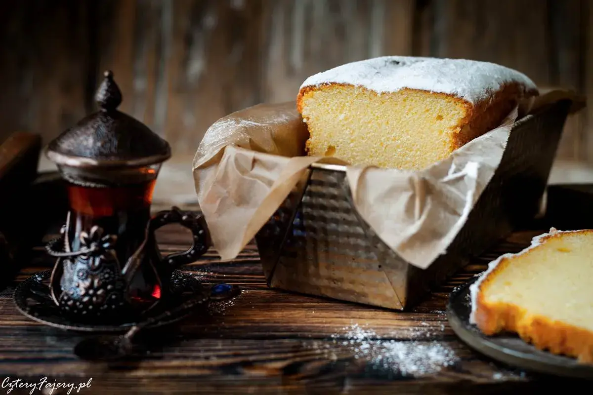 Puszysta babka włoska, oprószona cukrem pudrem, czeka na degustację obok aromatycznej herbaty w orientalnej filiżance.