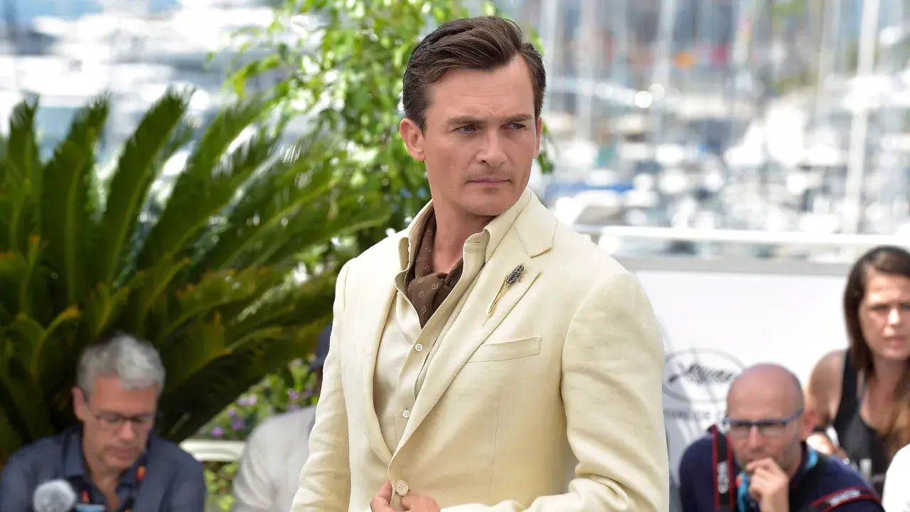 Hombre con un impecable corte de pelo old money, viste un traje de lino color crema y un pañuelo de seda.