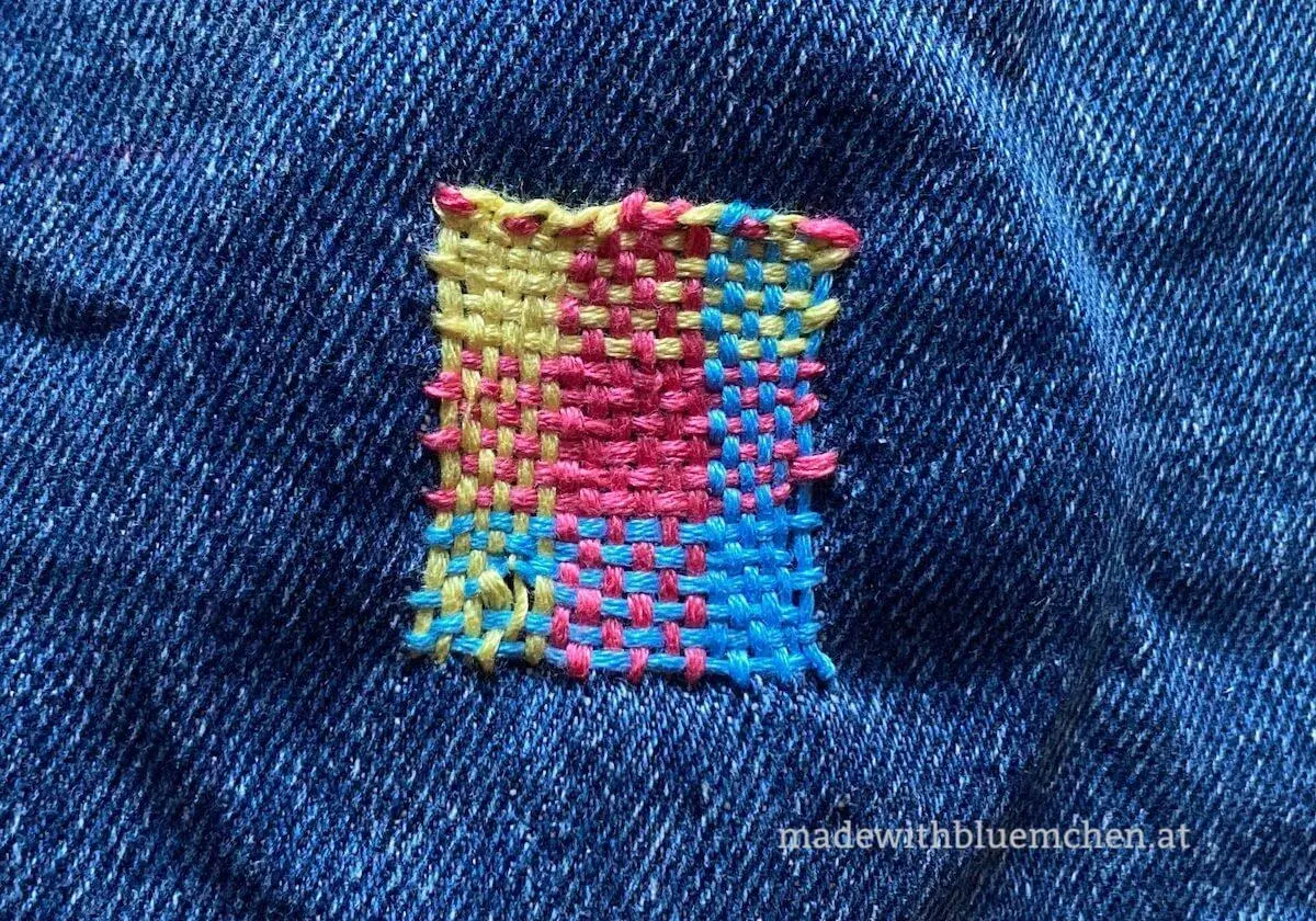 Buntes Quadrat aus Garn auf Jeansstoff, eine kreative kunststopfen anleitung.