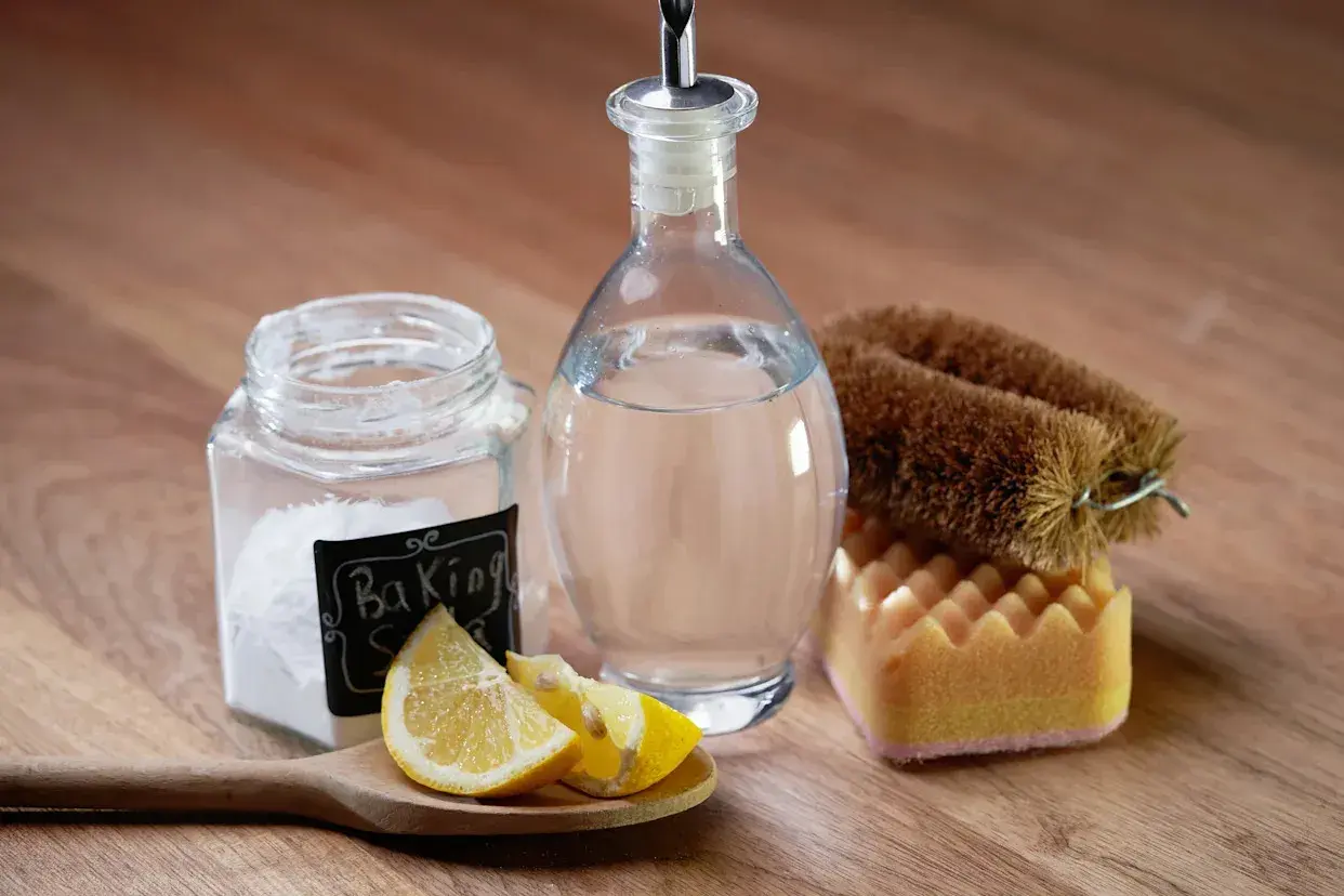 Natürliche Reinigungsmittel: Natron, Zitrone und Essigreiniger-Flasche mit Bürste und Schwamm.