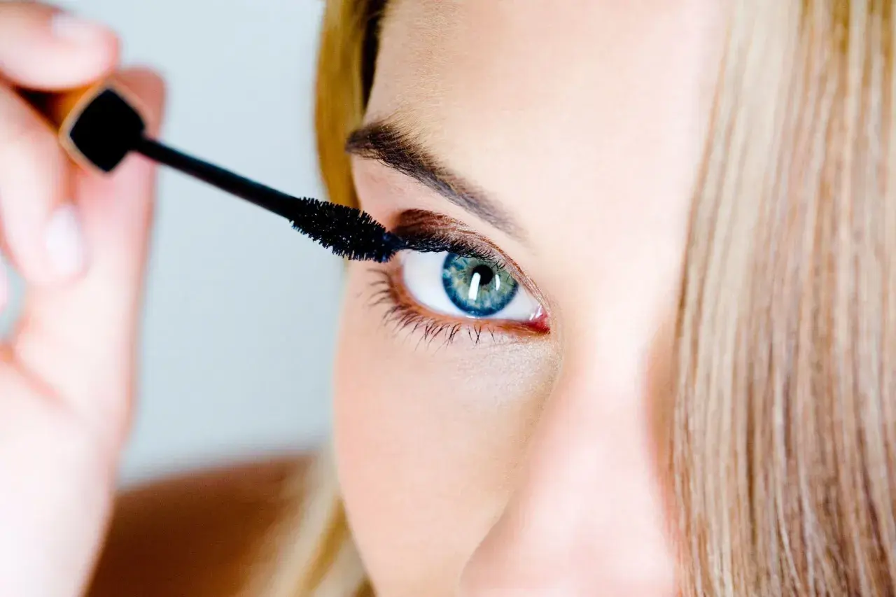 Une femme applique du mascara. Pour savoir comment enlever du mascara waterproof, il faut un bon démaquillant.