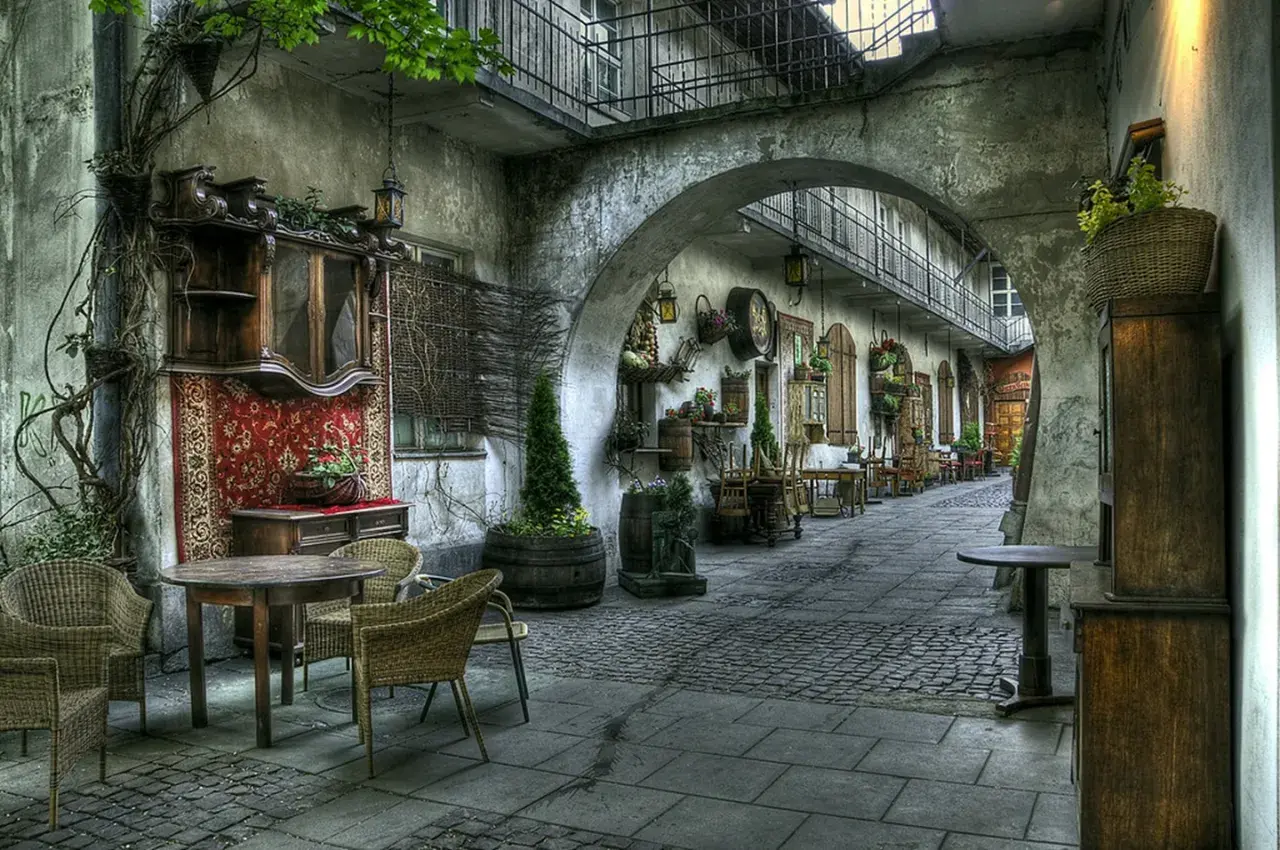 Urokliwy dziedziniec w Krakowie, gdzie antyczne meble i dywany przywołują ducha historii, niczym najcenniejsze zabytki krakowa.