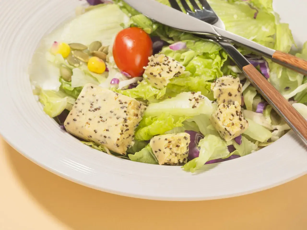 Salade fraîche avec cubes de tofu aux graines, maïs, tomate et graines de courge. Parfait pour savoir que manger après le sport.