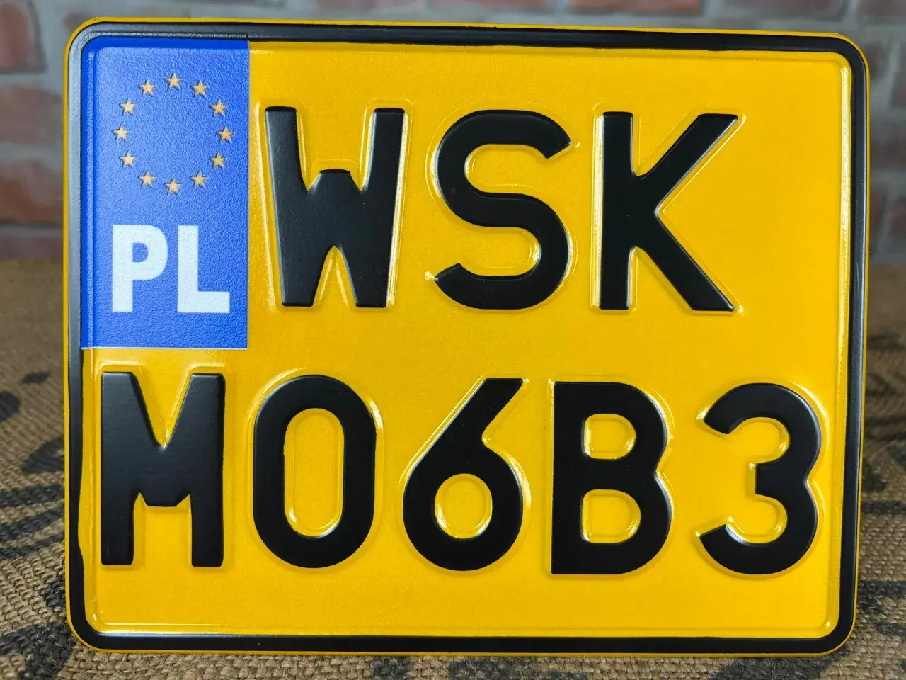Żółta tablica rejestracyjna z literami WSK i cyframi MO6B3. PL oznacza Polskę.