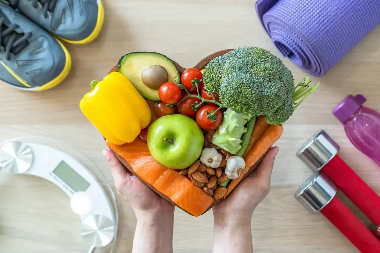 Un cuore di cibo sano: salmone, verdure, frutta, frutta secca e aglio. Capire cosa sono i carboidrati è fondamentale per una dieta equilibrata.