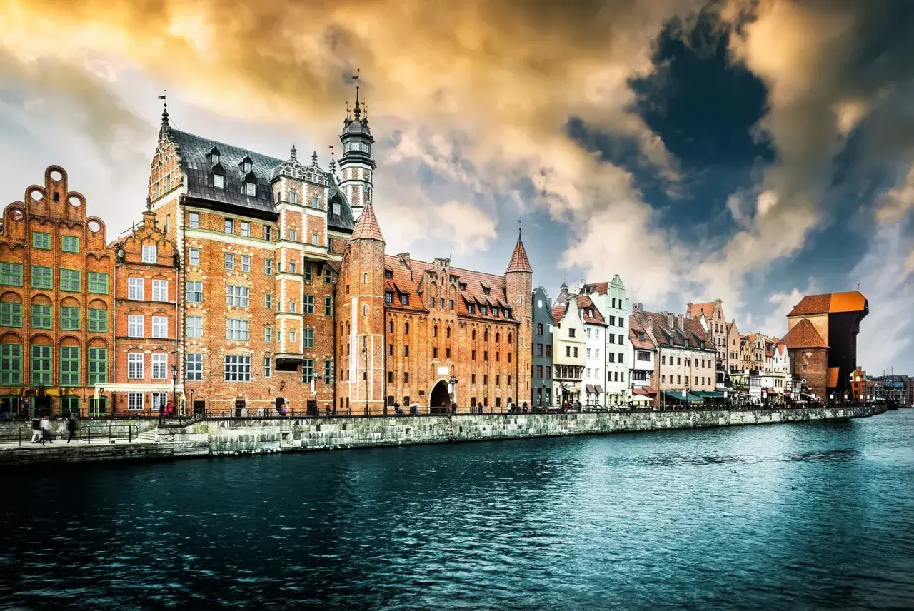 Malownicze kamienice nad Motławą, symbol gdańsk stare miasto, pod burzowym, złocistym niebem.
