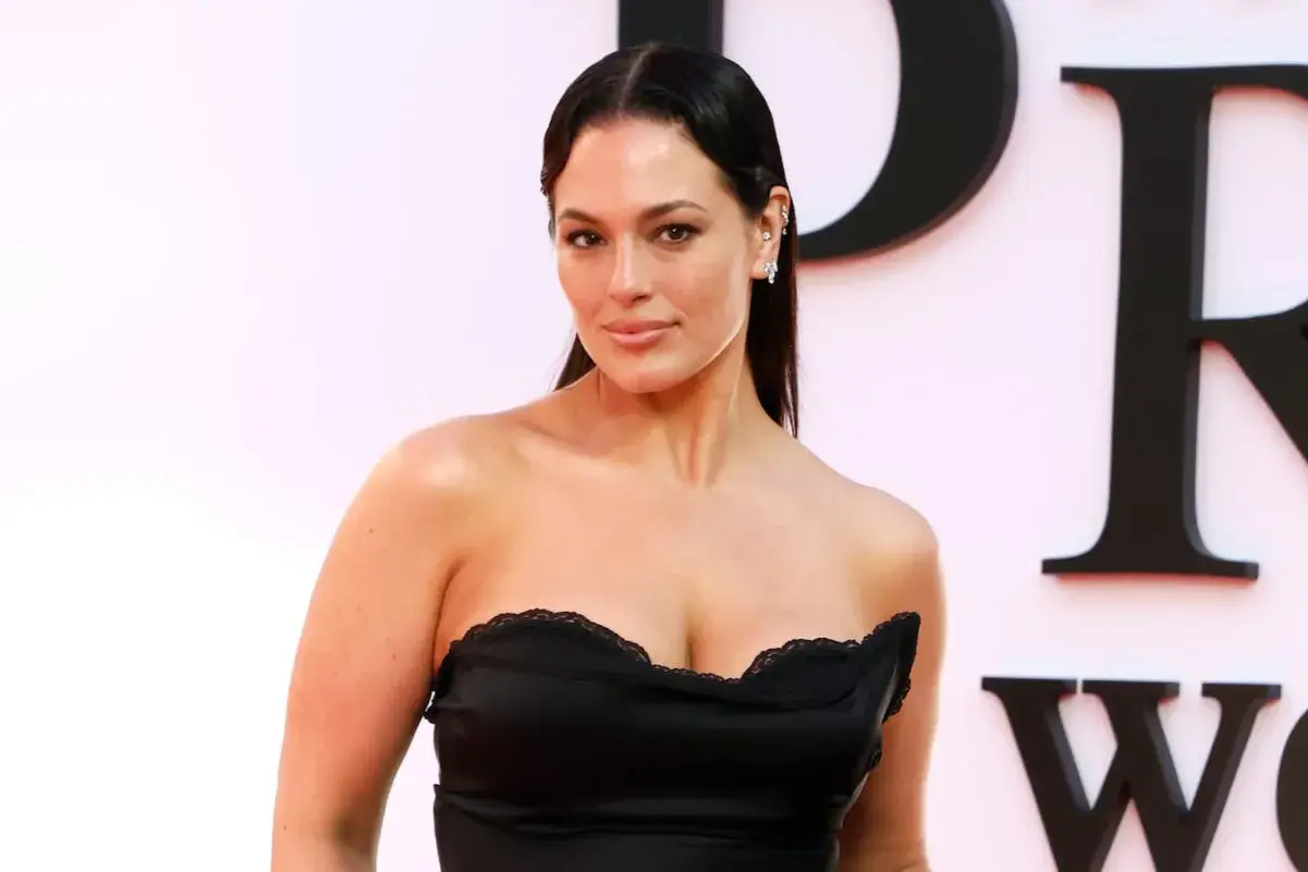 Ashley Graham posa con un vestido negro sin tirantes, luciendo elegante y segura.