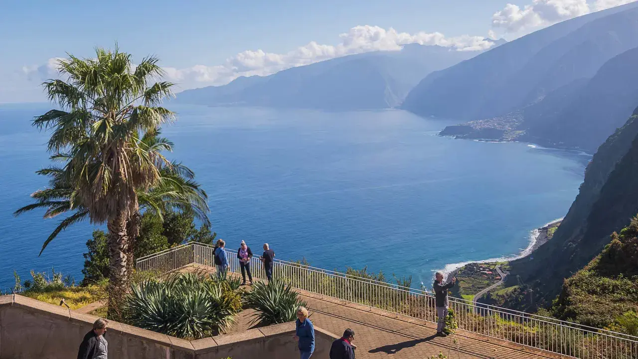 Blick auf Ribeira da Janela mit Palmen und dem tiefblauen Meer. Touristen genießen die Aussicht auf die Küste und die Berge.