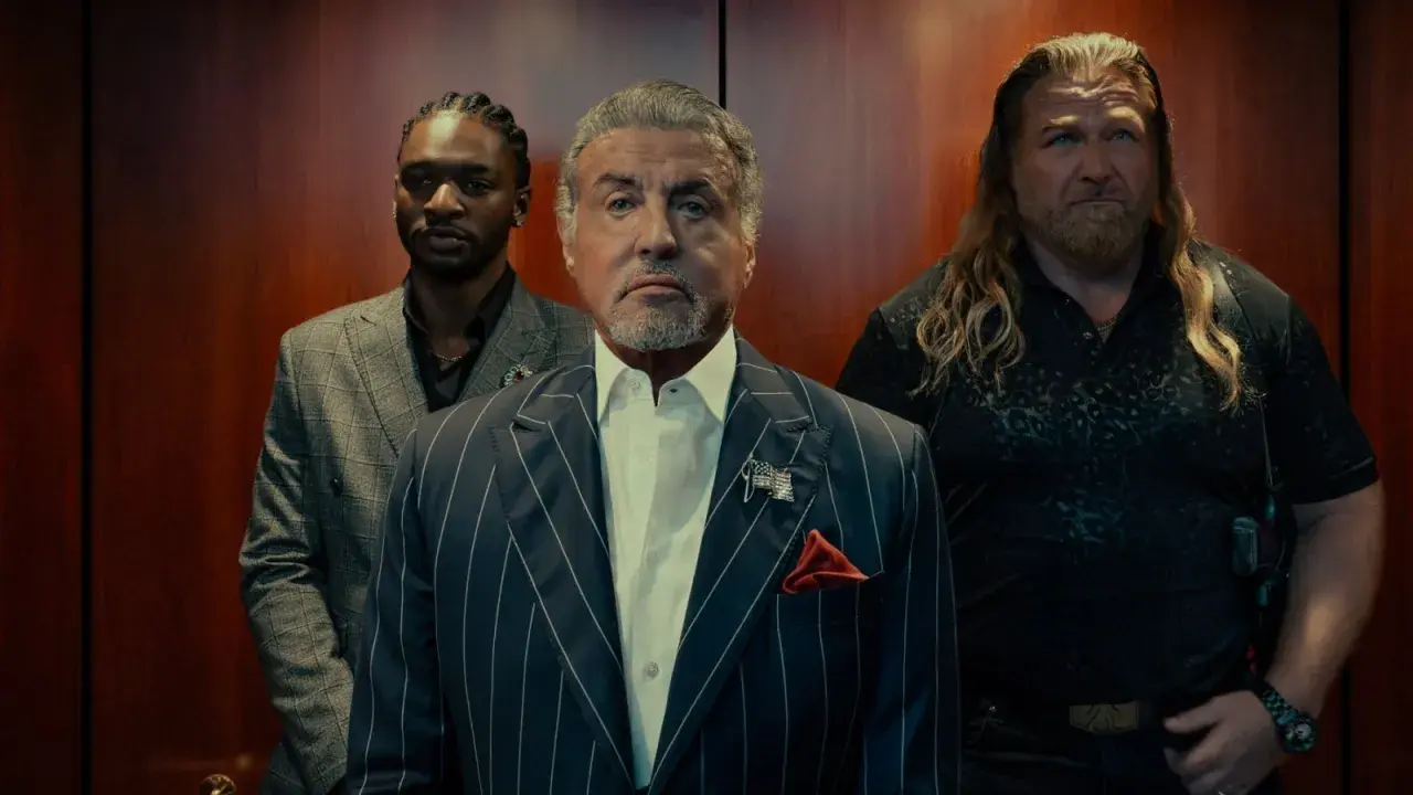 Sylvester Stallone i en serie, flankerad av två män i en hiss.