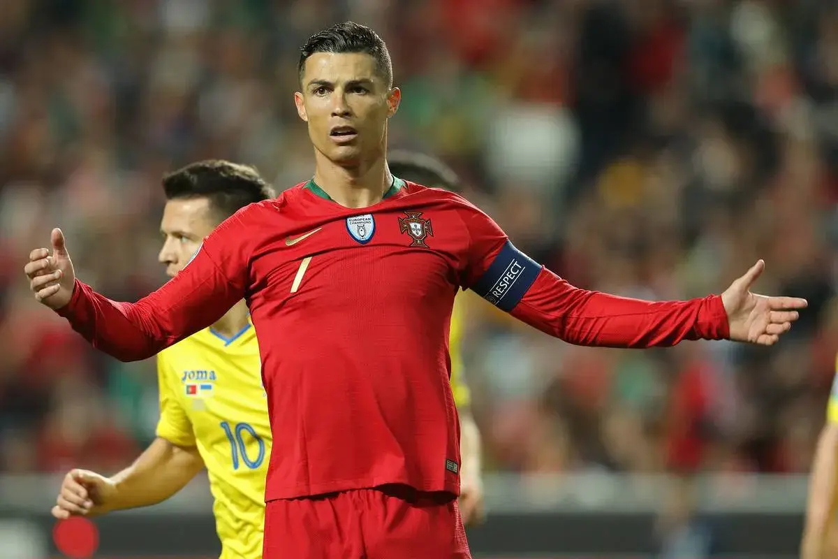 Cristiano Ronaldo w czerwonej koszulce Portugalii, z opaską "RESPECT", na tle drabinki rozgrywek Mistrzostw Europy w piłce nożnej.