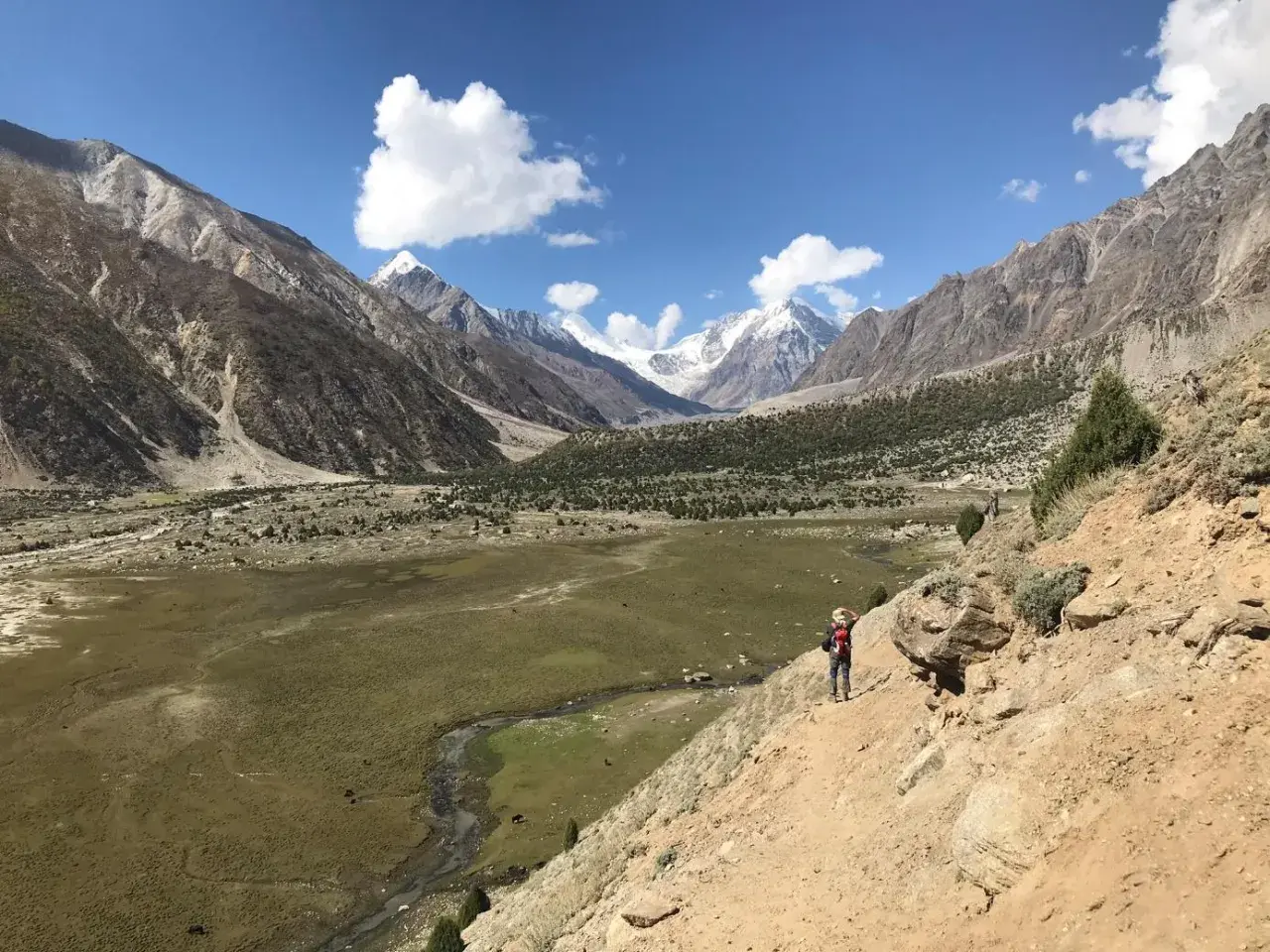 Wanderer auf einem Pfad im Rupal-Tal, umgeben von majestätischen Bergen und grünen Tälern.