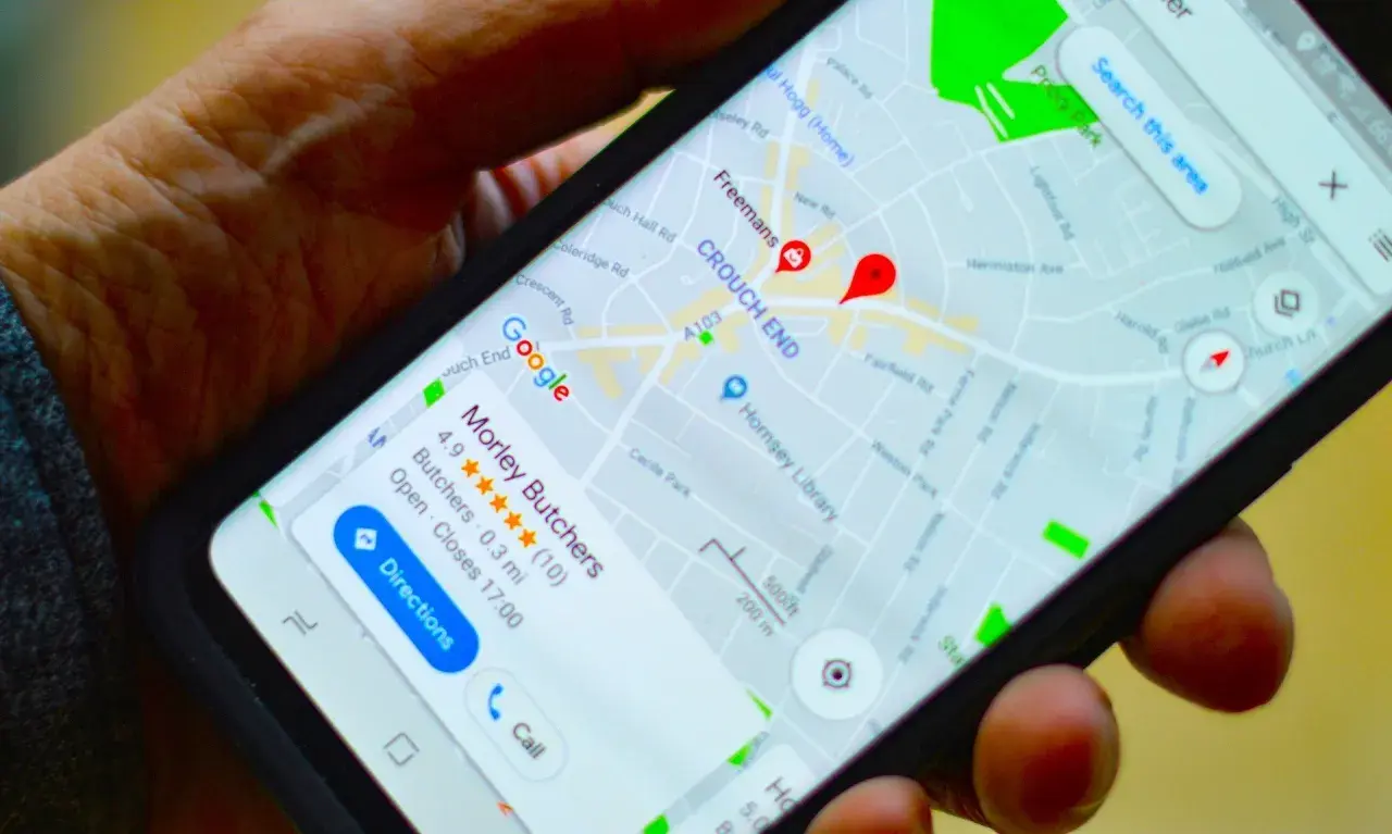 Dłoń trzyma smartfon z mapą Google. Widoczna jest pinezka Google wskazująca lokalizację "Morley Butchers".