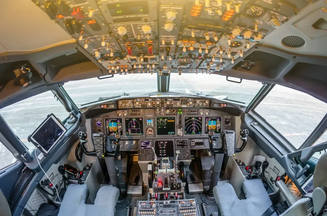 Kokpit samolotu a320neo. Widok z fotela pilota na zaawansowane przyrządy, ekrany i dźwignie sterowania.