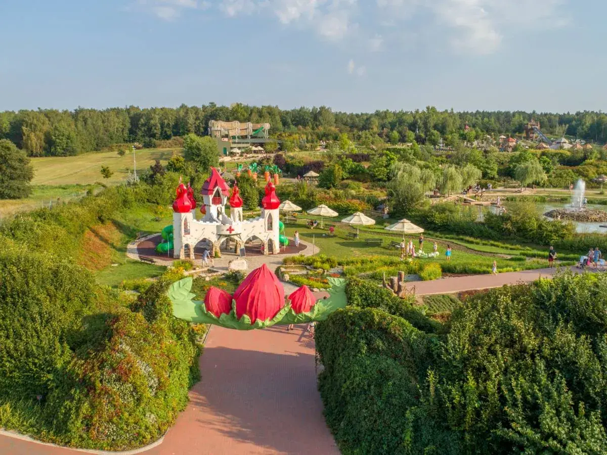 Bajkowy zamek i plac zabaw, gdzie są magiczne ogrody. Dzieci bawią się wśród zieleni i kwiatów.