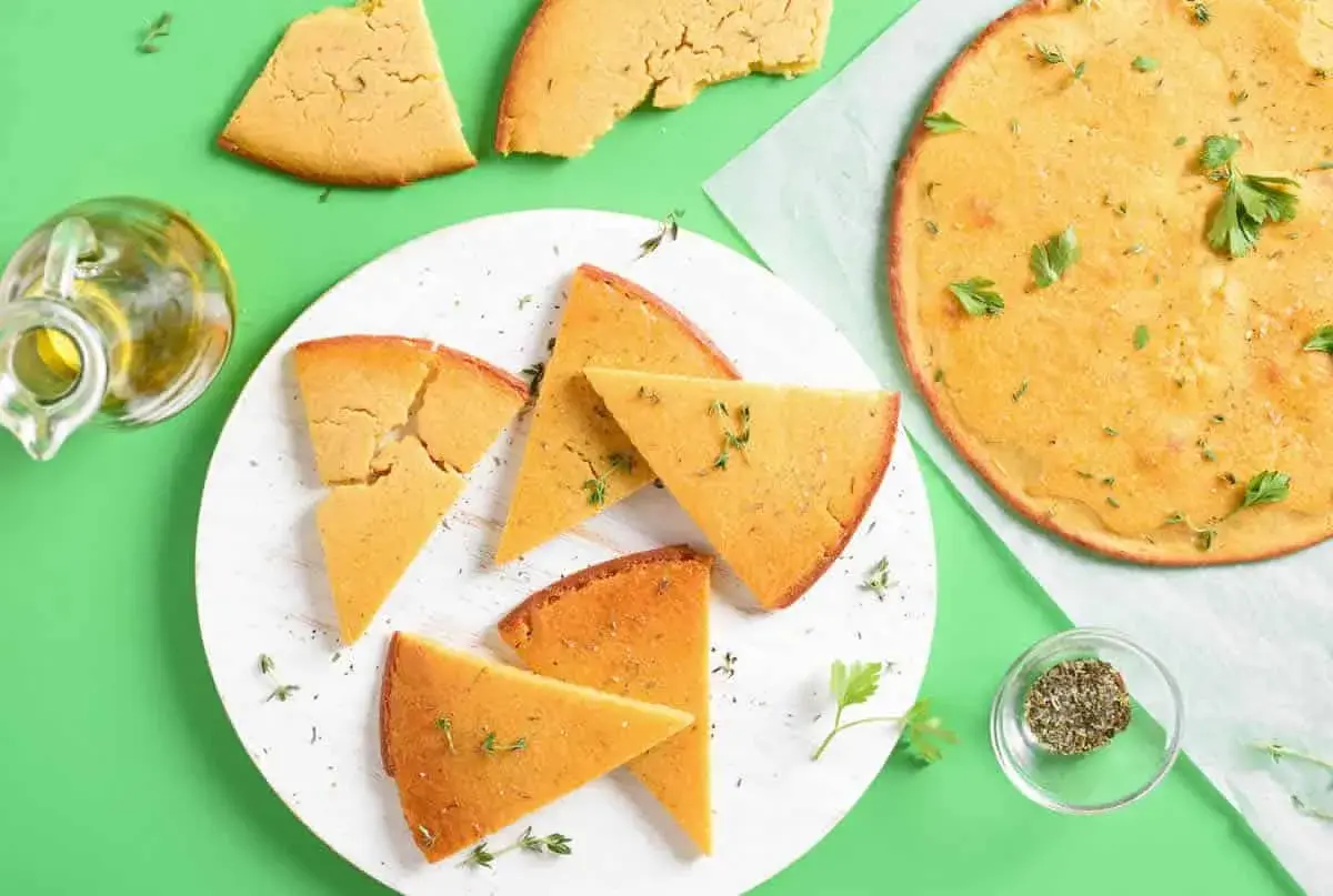 Une délicieuse socca coupée en parts, garnie d'herbes fraîches. Parfait pour une recette facile et savoureuse.
