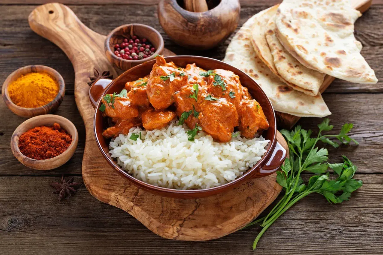 Aksamitny kurczak tikka masala z ryżem basmati, podany z plackami naan i aromatycznymi przyprawami.