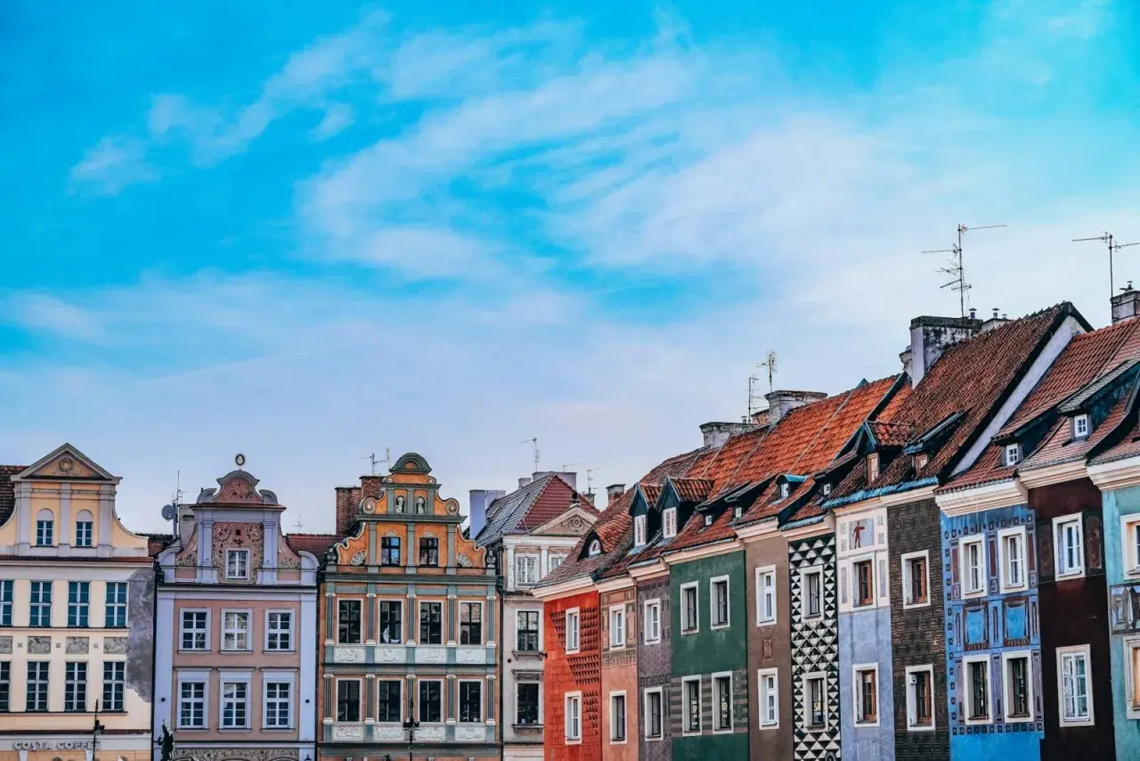 Kolorowe kamienice na Starym Rynku w Poznaniu, województwo wielkopolskie, pod błękitnym niebem.