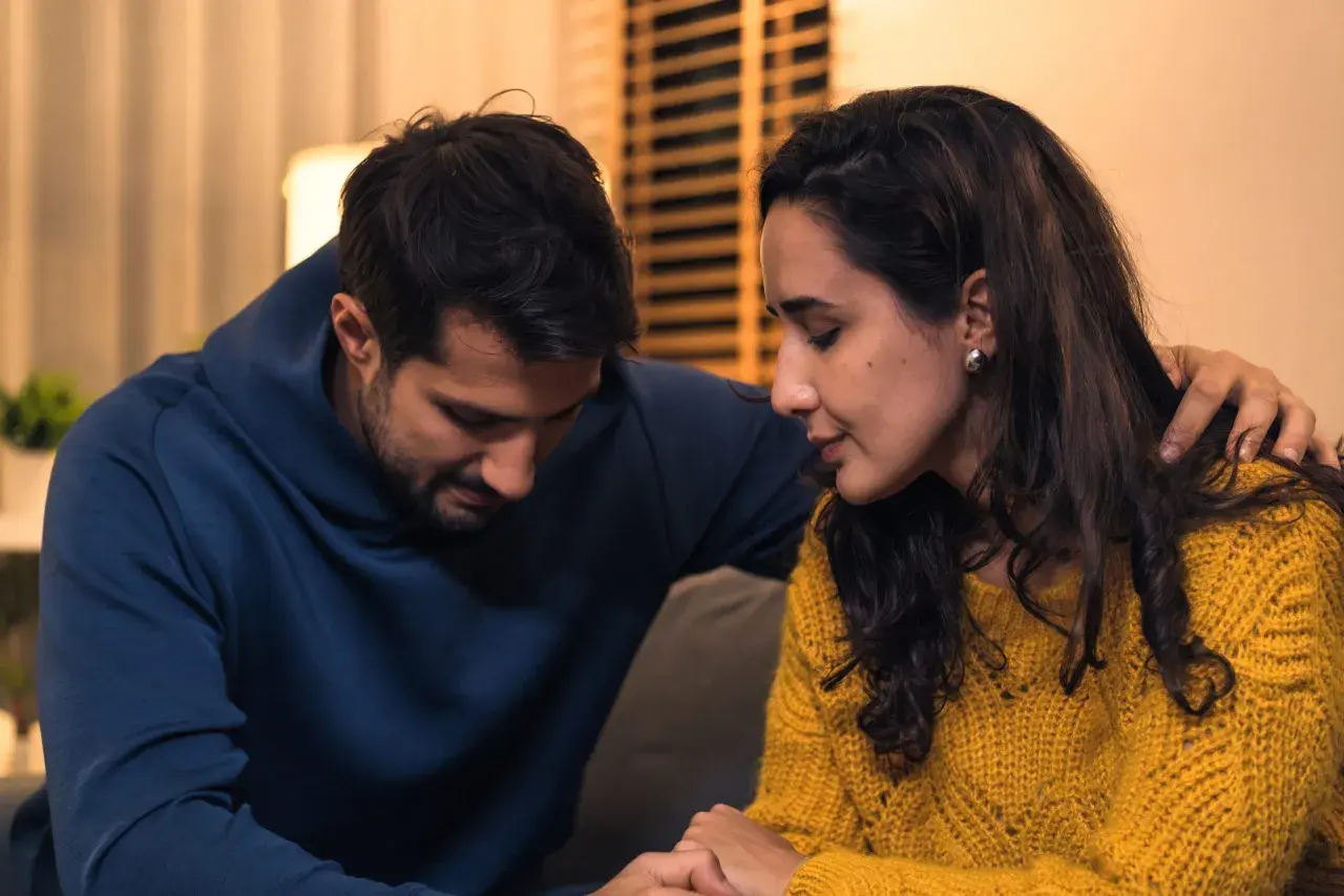 Een man met zijn arm om de schouder van een vrouw. Ze zitten dicht bij elkaar, wat hoop geeft op de kans van slagen relatie na vreemdgaan.