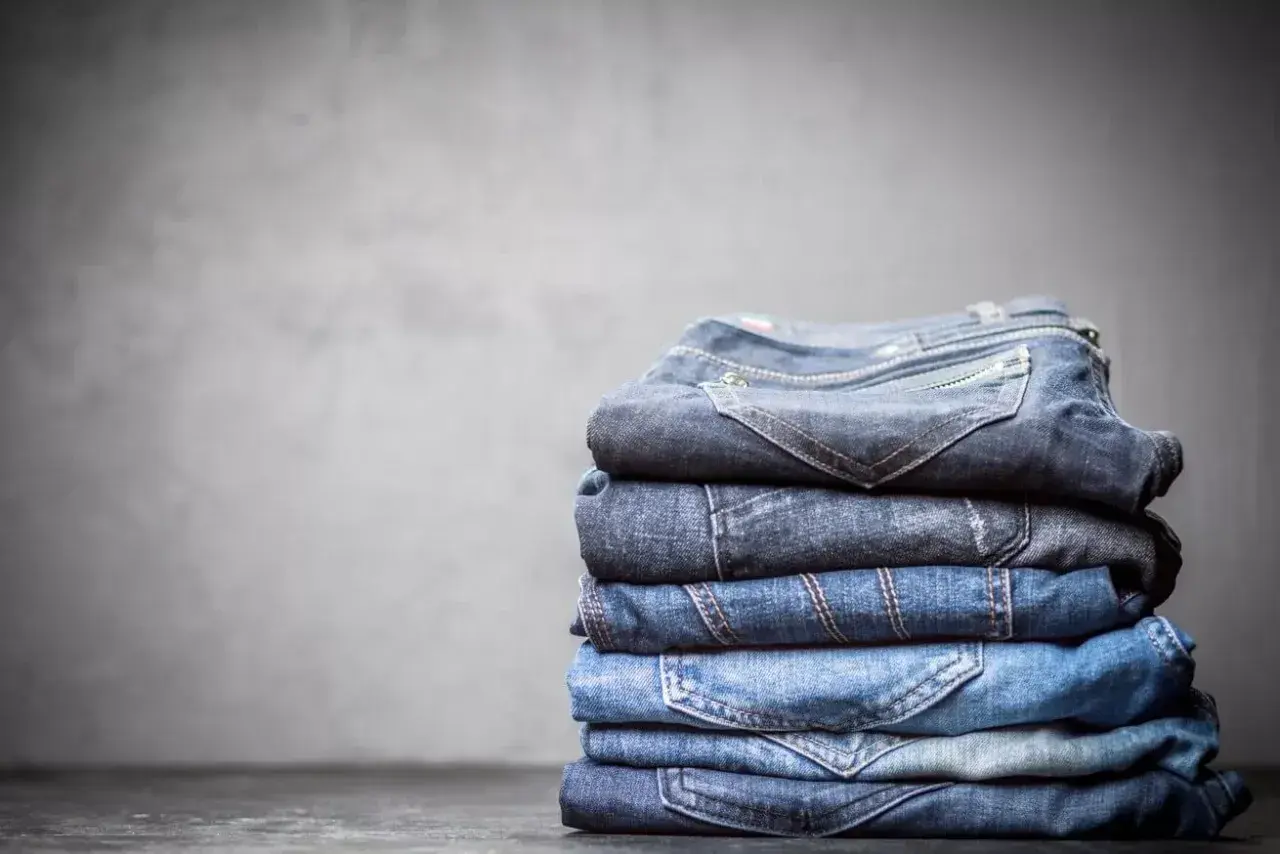 Stosik dekatyzowanych jeansów w różnych odcieniach niebieskiego, z widocznymi kieszeniami i szwami.