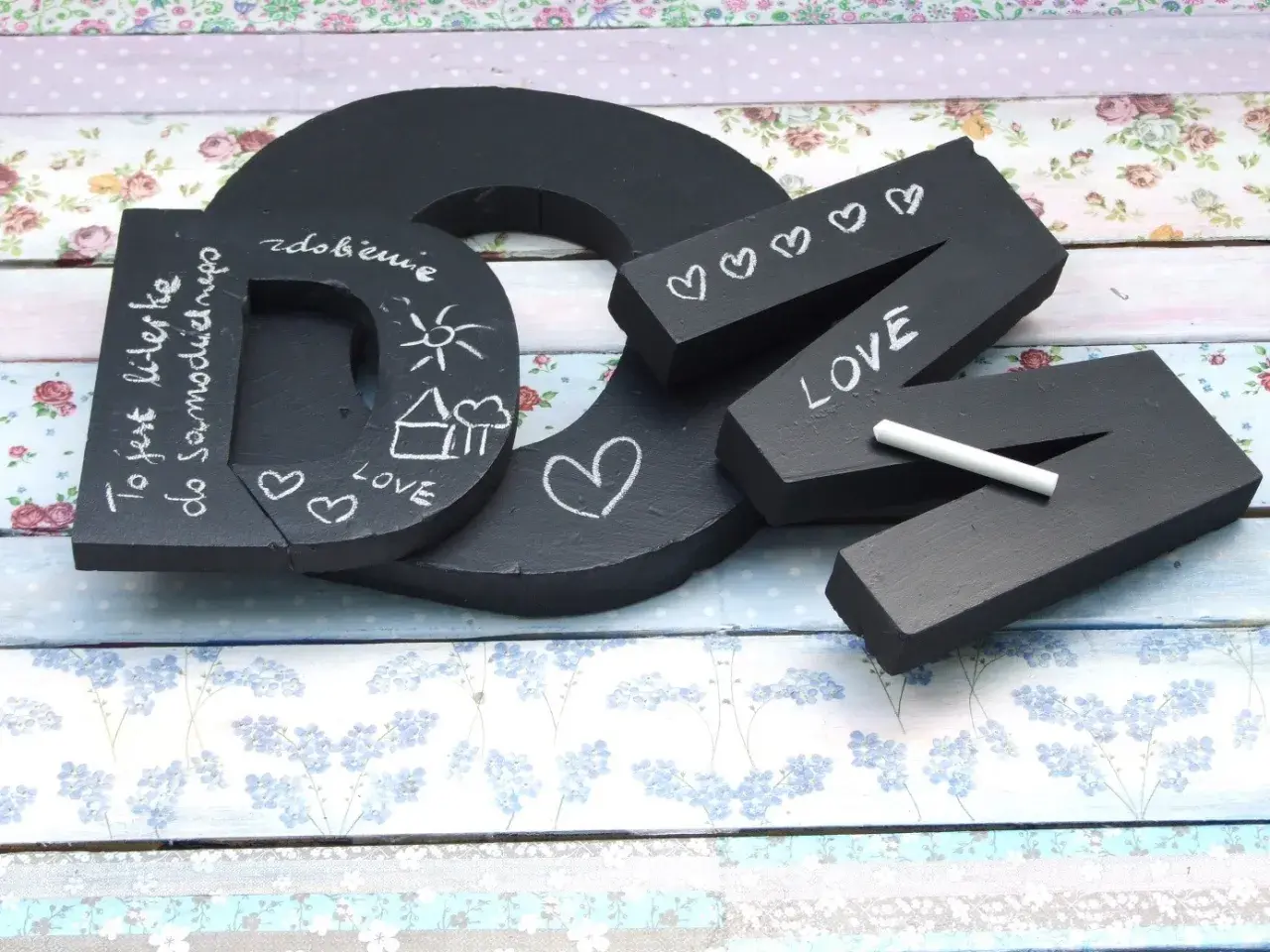 Czarna litera "D" z napisem "To jest literka do samodzielnego..." i rysunkami. Obok litery "N" z napisem "LOVE" i serduszkami, wykonane w stylu pismo kaligraficzne.