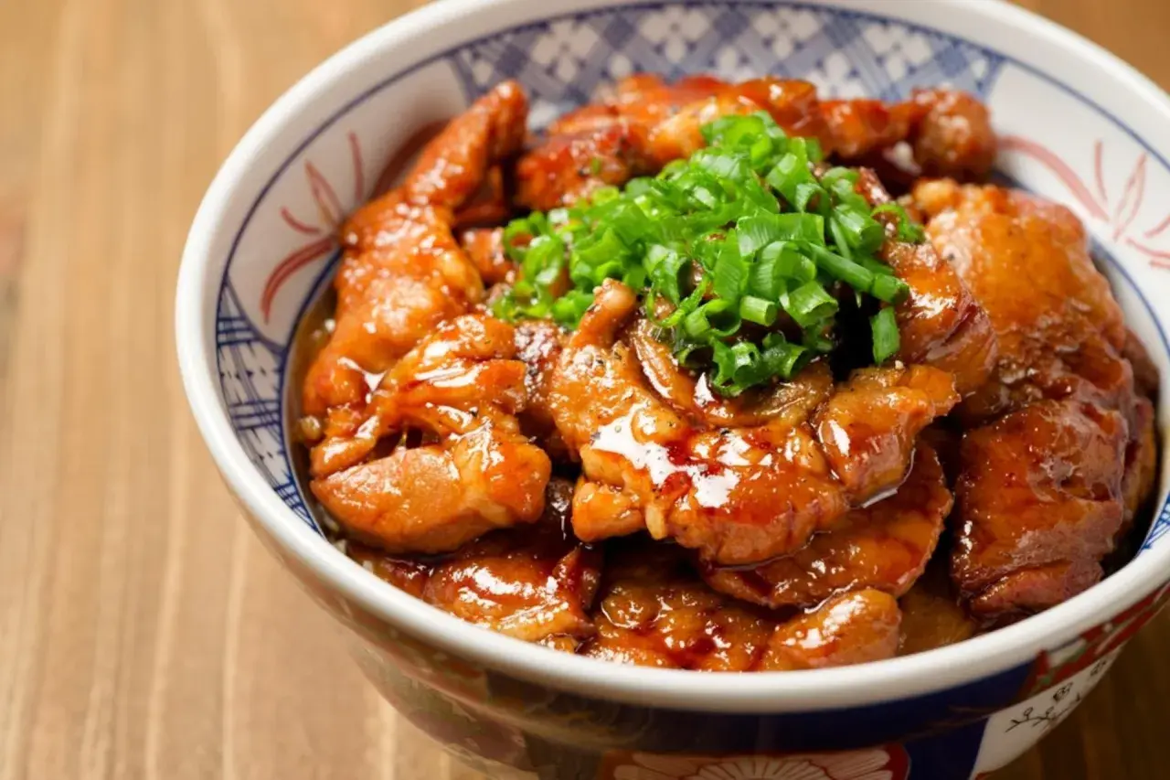 Miseczka z kurczakiem soboro w sosie teriyaki, posypana szczypiorkiem.