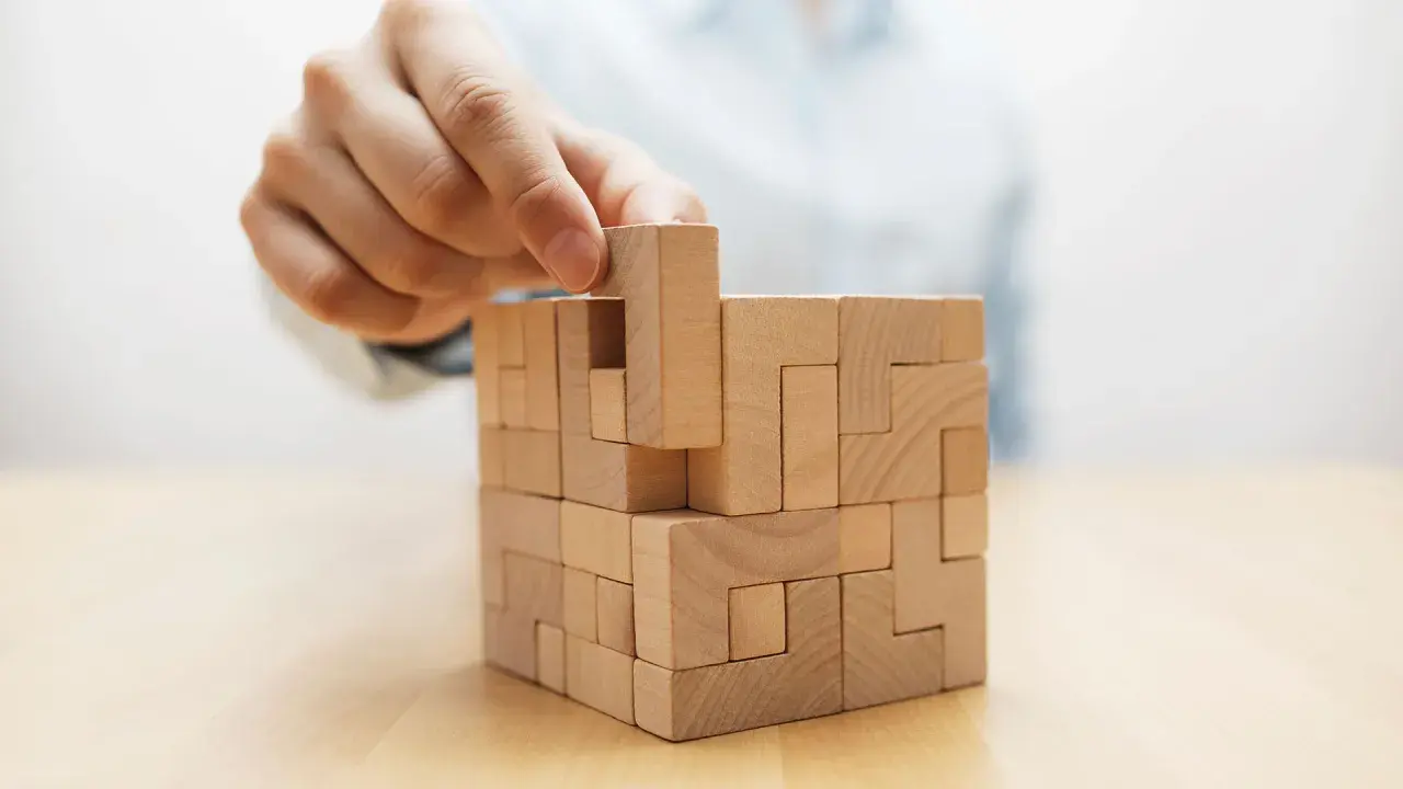 Mano che inserisce un pezzo di legno in un puzzle complesso, metafora di un efficace crisis management.