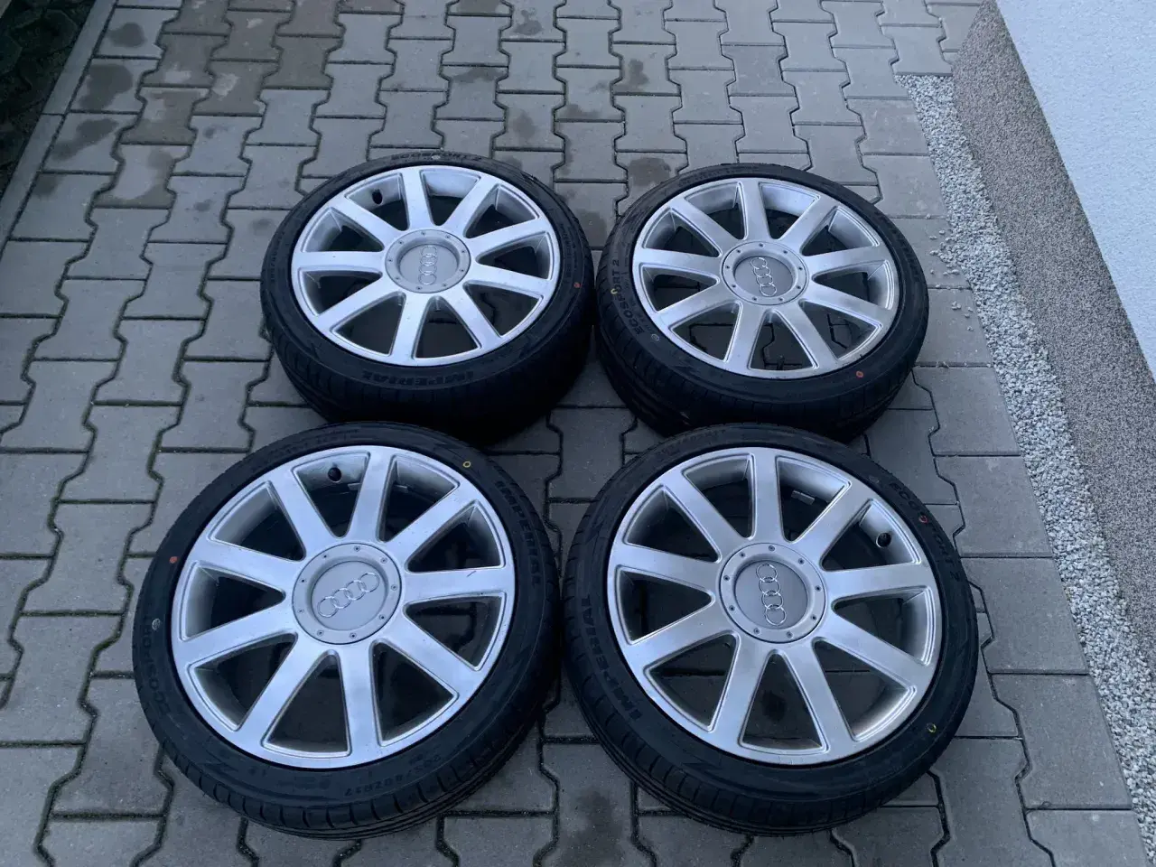 Cztery felgi aluminiowe z oponami do Audi A2. Rozmiar opon widoczny na jednej z nich to 205/55 R16.