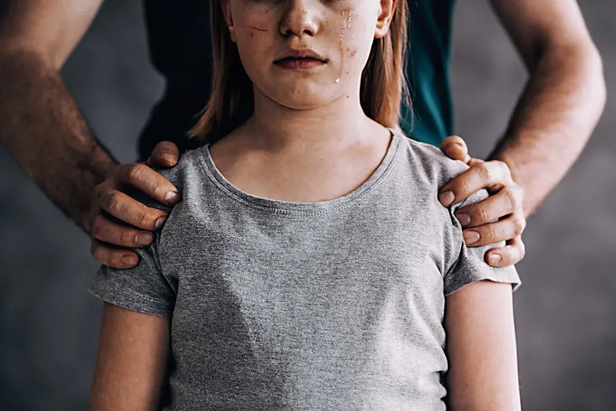 Zranione dziecko, łzy na twarzy. Dłoń na ramieniu. Jak udowodnić molestowanie po latach?