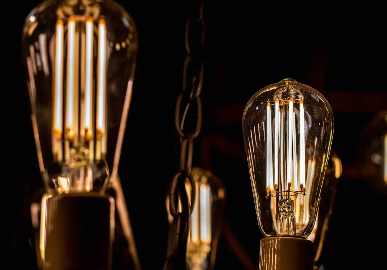 Bombillas led 15w de filamento, con luz cálida, colgadas de cadenas metálicas en la oscuridad.