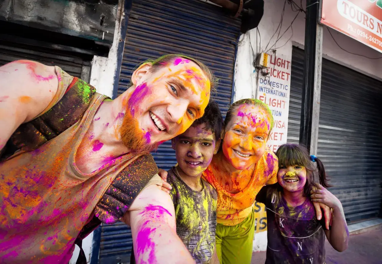 Fröhliche Familie feiert das Holi Festival in Indien, Gesichter und Kleidung bunt mit Pulverfarben bespritzt.