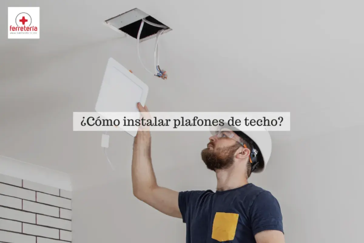 Hombre instalando bombillas plafon de techo, con casco y gafas de seguridad.