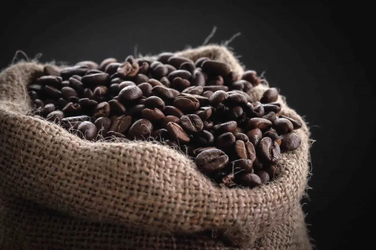 Un saco de arpillera lleno de granos de café tostados, una fuente natural de cafeína para el pelo.