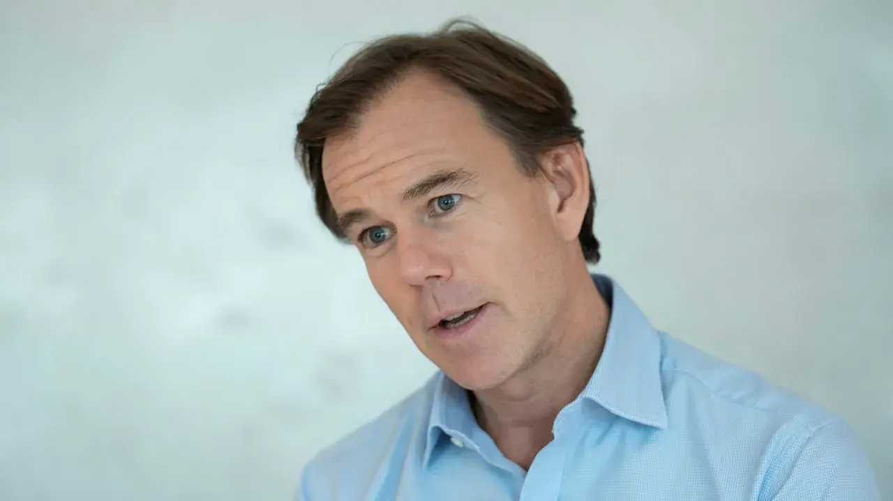 Karl-Johan Persson, i ljusblå skjorta, tittar åt sidan med ett engagerat uttryck.